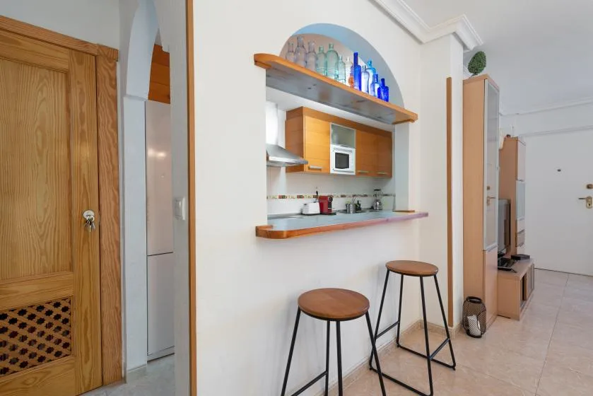 A compact kitchen with a breakfast counter and two stools.