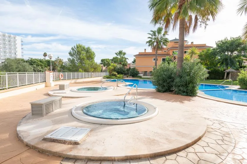 An outdoor pool area with a circular bubbling spa in the foreground.