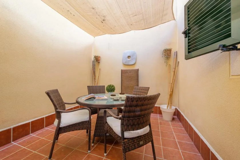 A small patio with a round table and wicker seating beneath a fabric canopy.