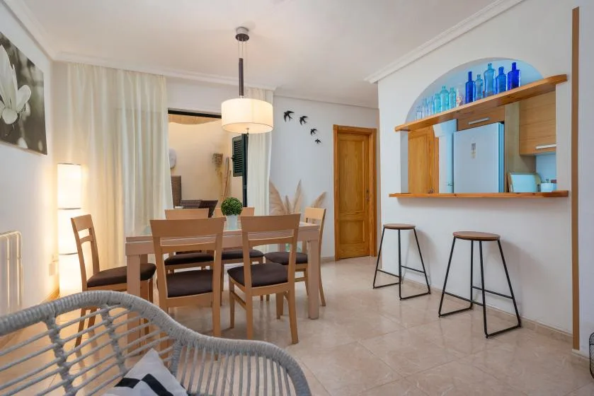 A dining area with a wooden table and chairs beside a counter with stools.