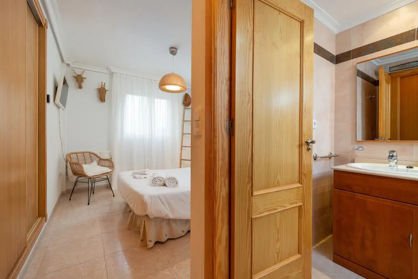 A bedroom with a bed and a chair is visible beside an adjoining bathroom.