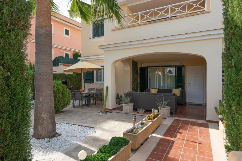 A patio with outdoor seating sits beside a shaded ground-floor terrace.