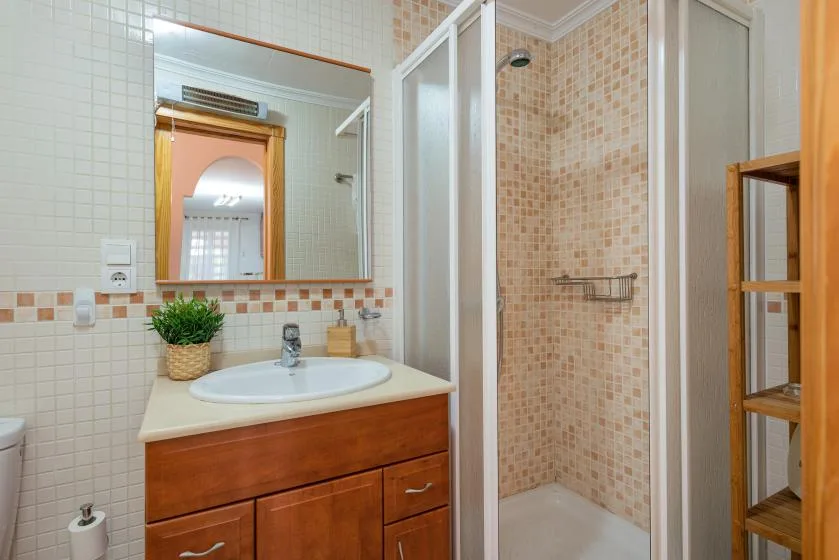 A tiled bathroom with a sink vanity and glass shower enclosure.