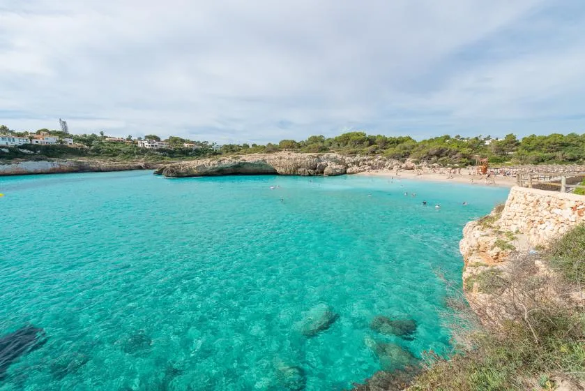 A turquoise coastal cove is bordered by rocky shoreline and low green vegetation.