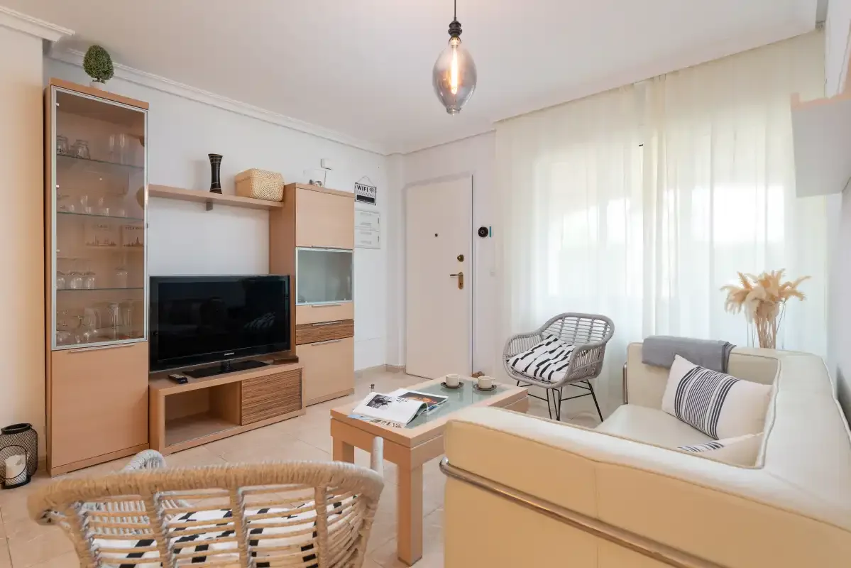 A bright living room with a television, seating, and a small coffee table.
