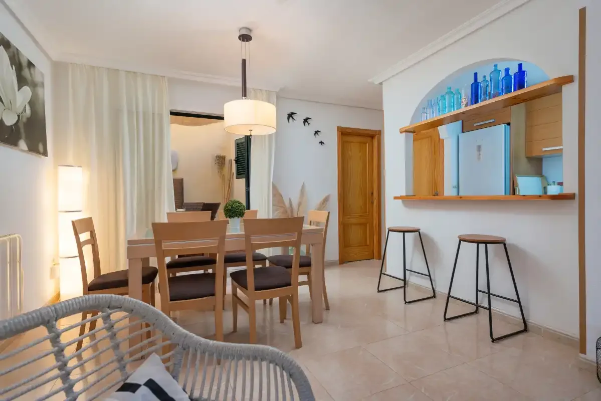 A dining area with a wooden table and chairs beside a wall bar.