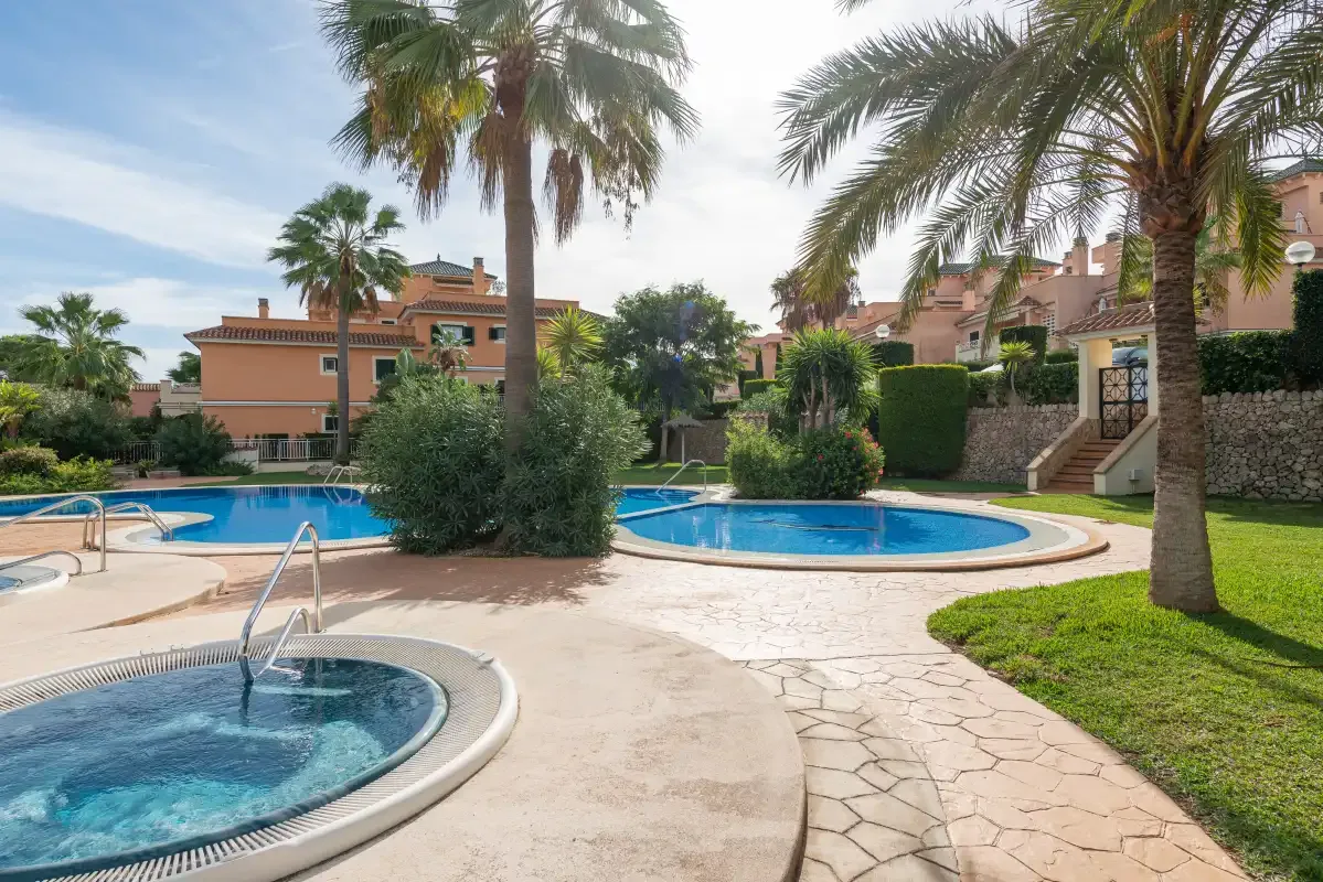 An outdoor pool area with palm trees and landscaped gardens.