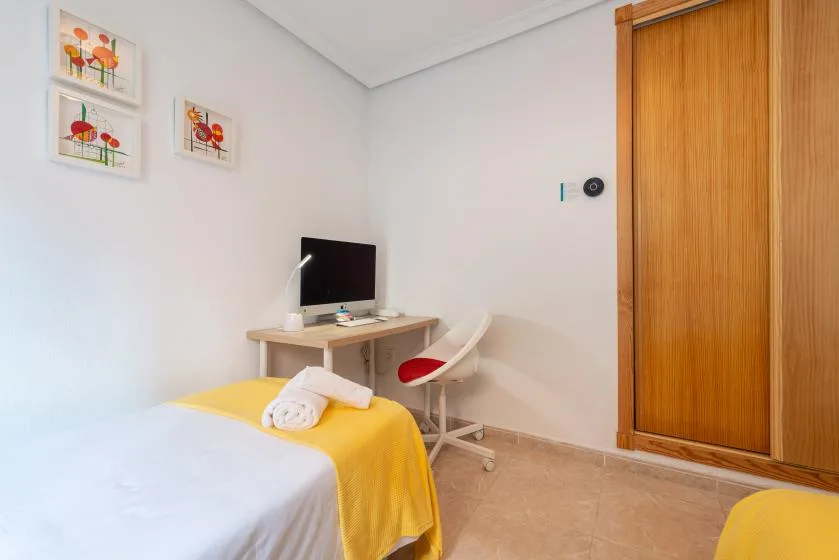 A bedroom with a bed, desk, and chair.