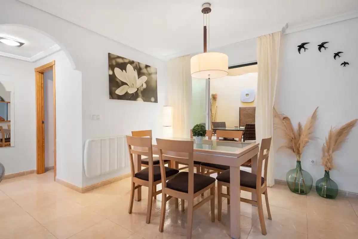 A dining area with a wooden table and chairs beneath a pendant light.