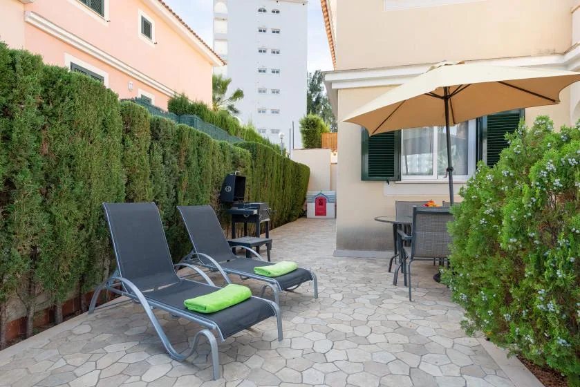 An outdoor patio with lounge seating, a dining table, and a large umbrella.