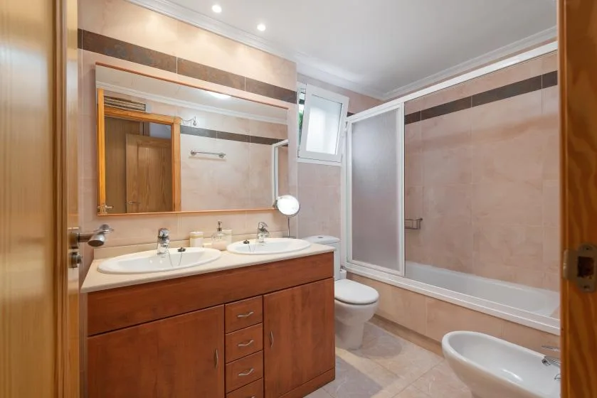 A bathroom with a double-sink vanity, toilet, and bathtub.