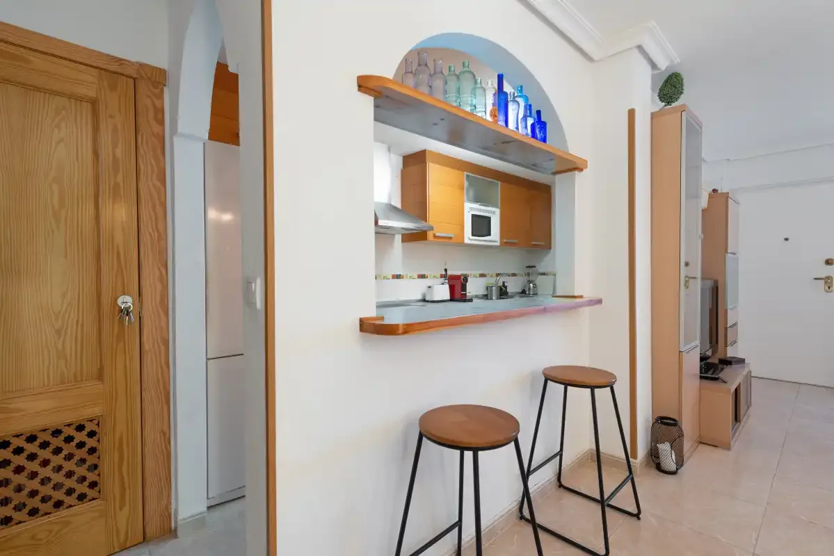 A compact kitchen with a breakfast counter and two stools.