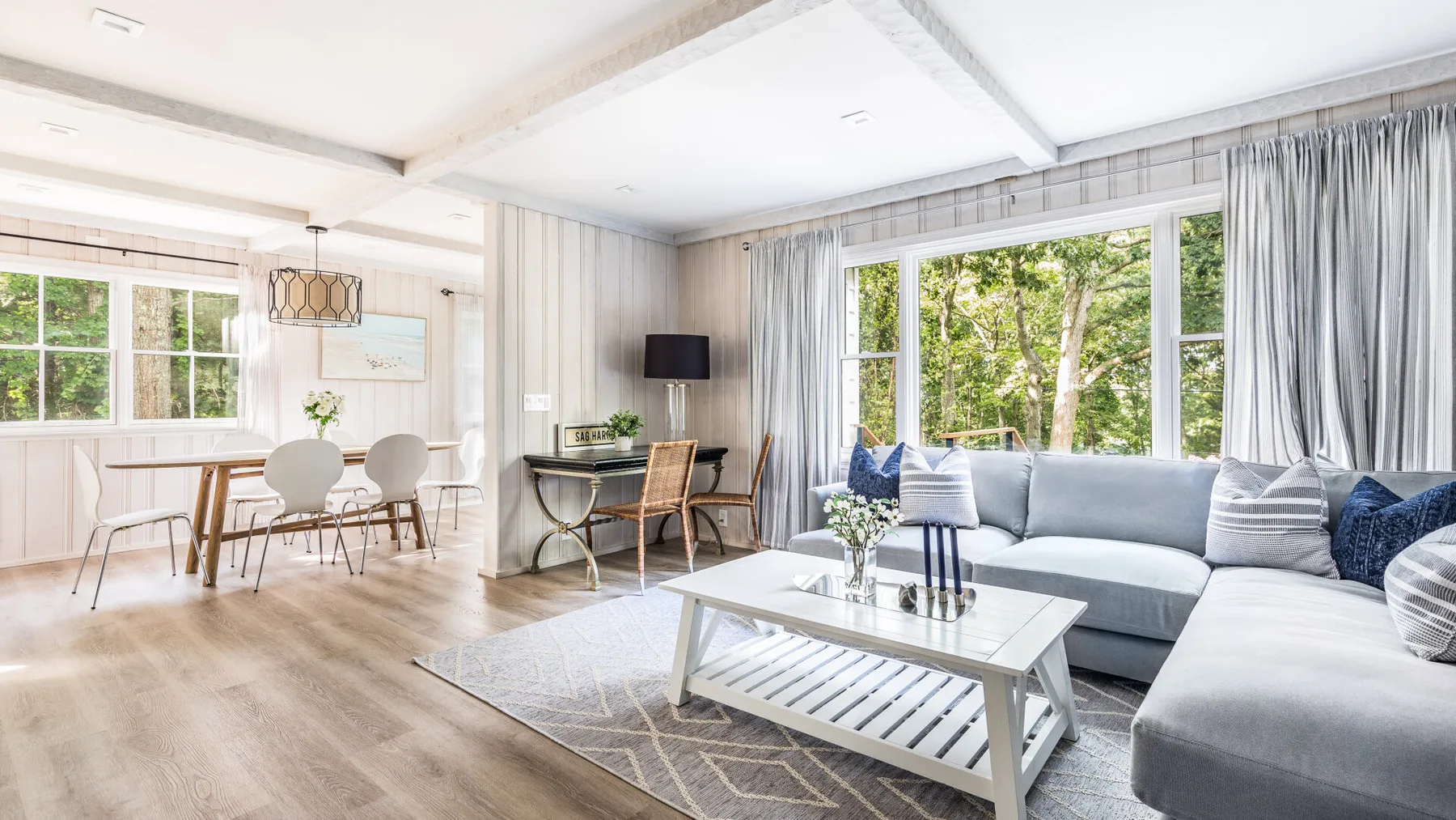 Una sala luminosa con un sofá seccional gris y una mesa de centro de vidrio.