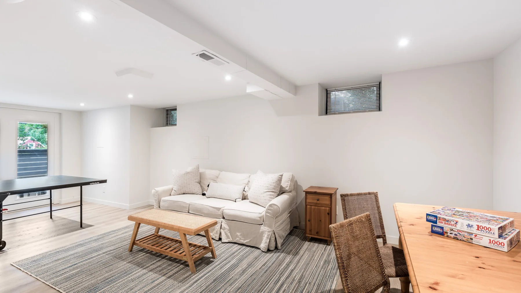 Una luminosa sala de estar y comedor con asientos claros y una mesa de madera.