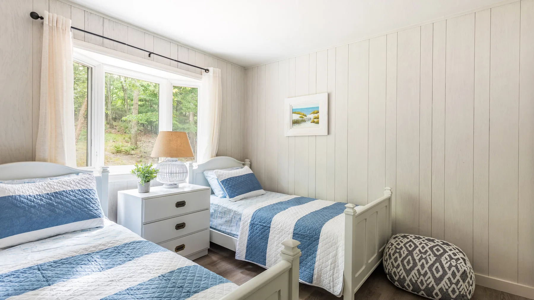 Un dormitorio luminoso con dos camas vestidas con ropa de cama azul y blanca.