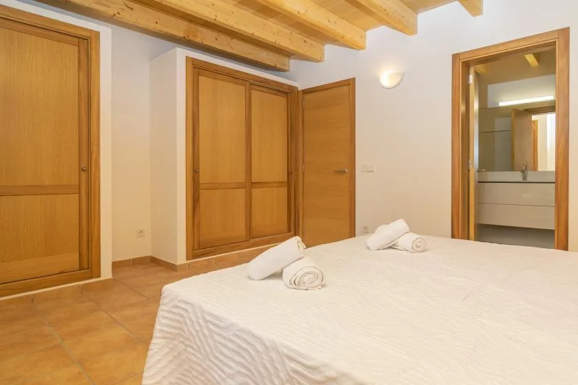 Un dormitorio con una cama, puertas de madera y vigas de techo a la vista.