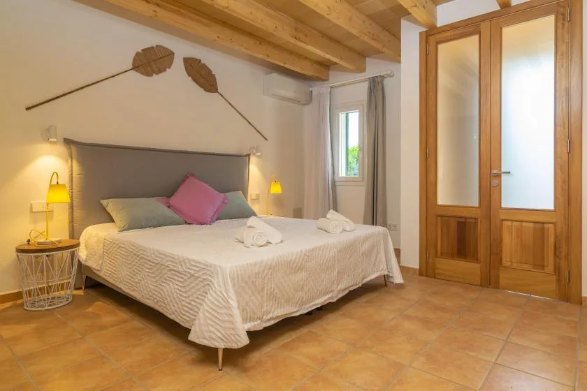 Un dormitorio con una cama doble, mesitas de noche y puertas dobles de madera.