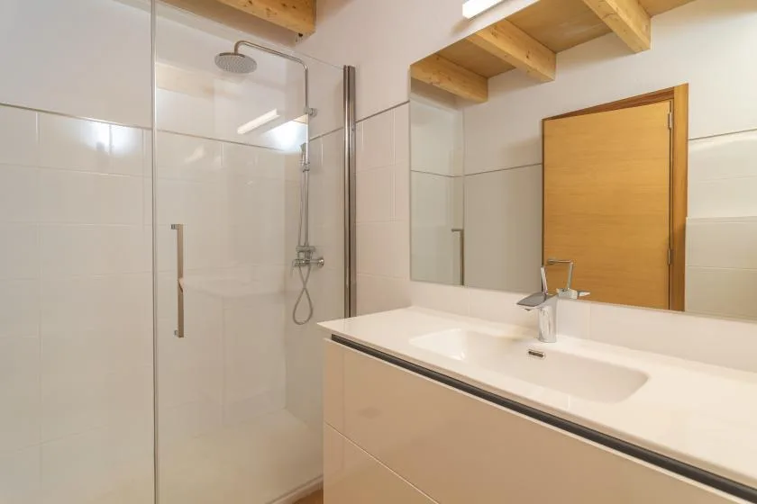 Un baño luminoso con ducha y una amplia encimera con lavabo.