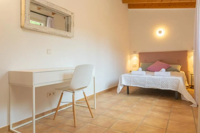 Un dormitorio con una cama y un escritorio junto a una silla blanca.