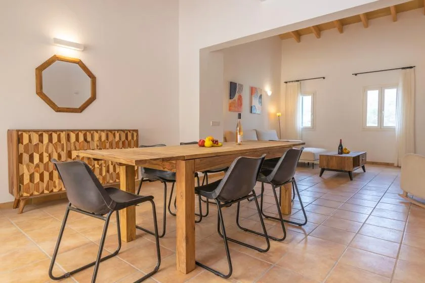 Un comedor con una mesa larga de madera y sillas bajo vigas expuestas.
