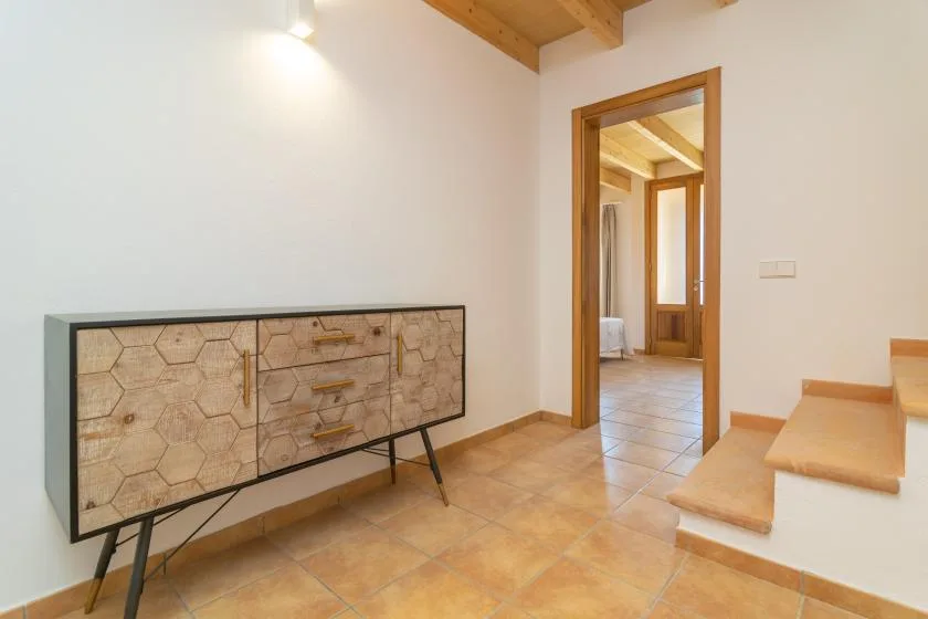 Una entrada con suelo de baldosas, un mueble de madera y una puerta abierta.