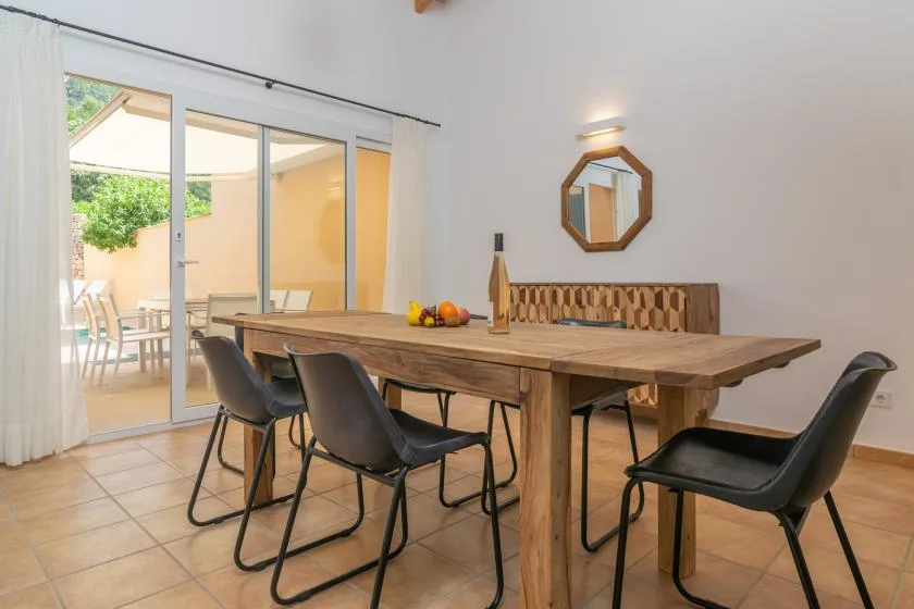 Comedor con una mesa grande de madera y sillas junto a puertas de cristal.