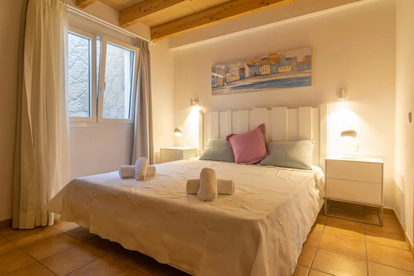 Un dormitorio con iluminación cálida y una cama bajo un cuadro enmarcado.