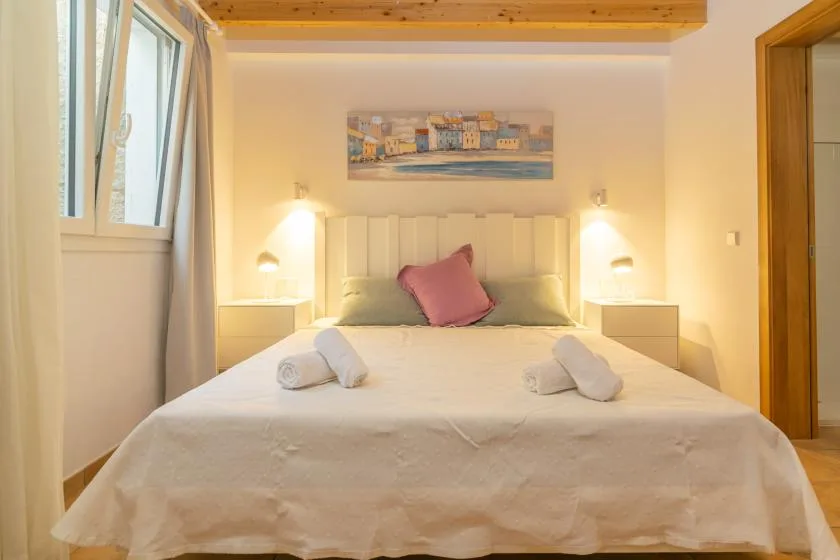 Un dormitorio con una cama bien tendida y un cuadro colorido encima.