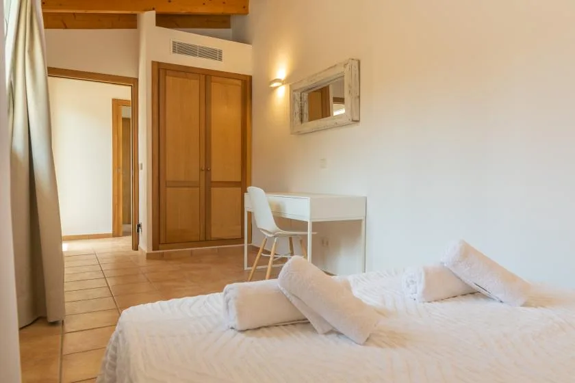 Dormitorio con una cama, un pequeño escritorio y puertas de armario de madera.