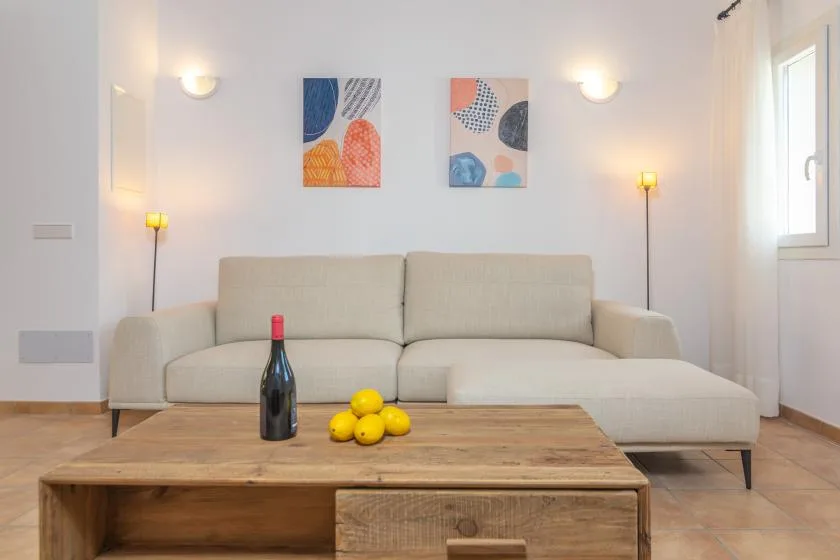 Una sala luminosa con un sofá seccional beige y una mesa de centro de madera.