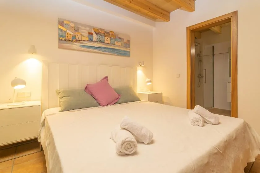 Un dormitorio con una cama grande, mesitas de noche y una puerta hacia una ducha.