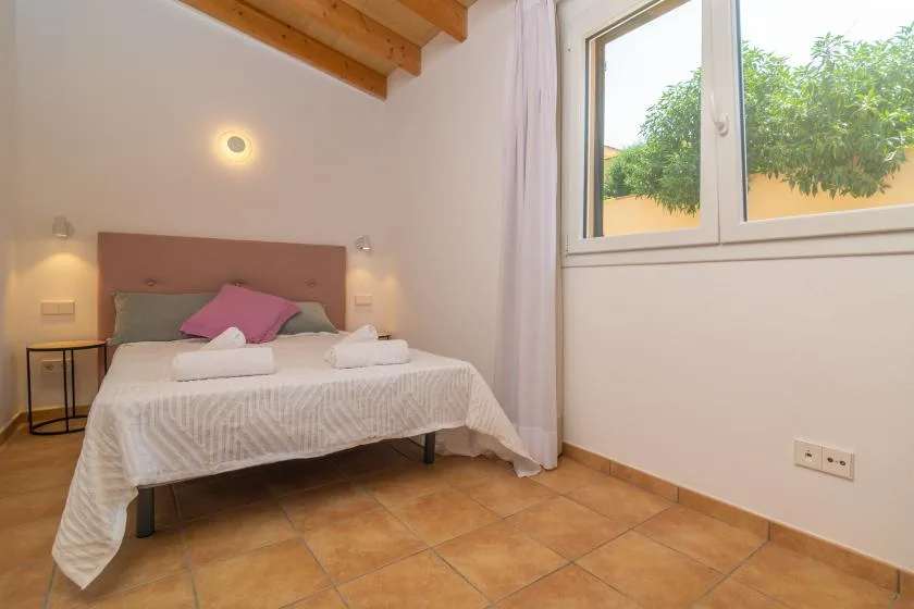 Un dormitorio con una cama bajo un techo de madera y una ventana grande.
