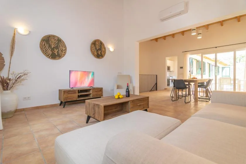 Una sala luminosa con asientos, un televisor y un comedor.