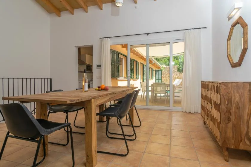 Comedor con una mesa de madera y sillas junto a puertas de vidrio que dan a un patio.