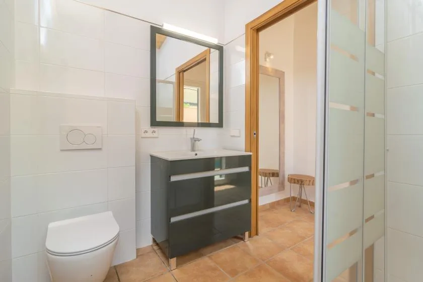 Un baño alicatado con lavabo, espejo y ducha.