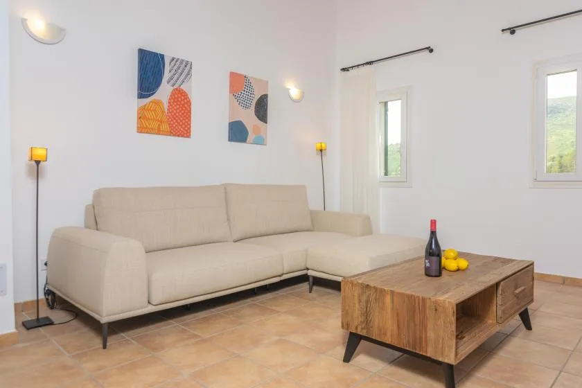 Una sala de estar luminosa con un sofá seccional beige y una mesa de centro de madera.