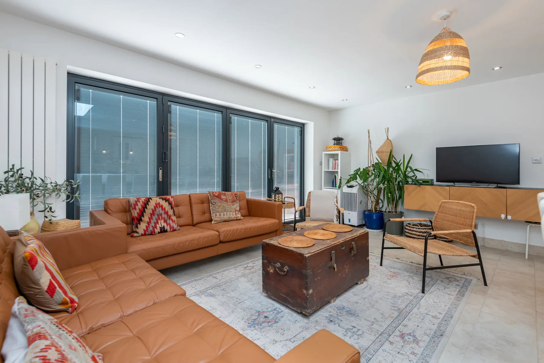 A bright living room with leather seating, a coffee table, and a television.
