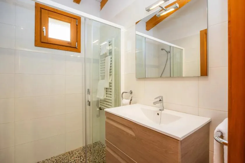 A tiled bathroom with a glass shower, vanity, and wall mirror.