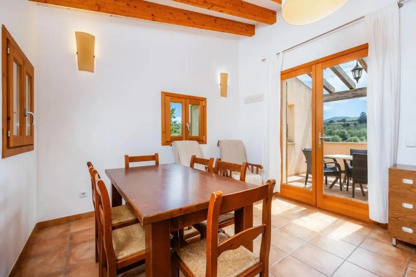 A dining area with a wooden table and chairs beside glass doors opening to a terrace.