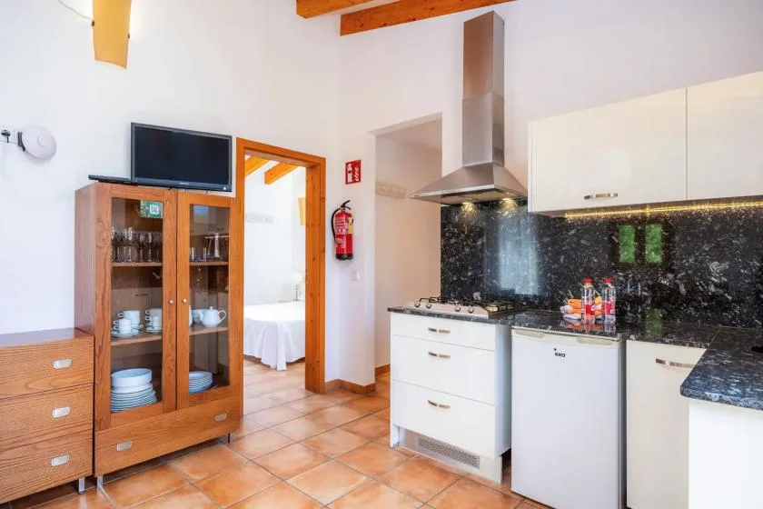 A kitchen with white cabinets, a cooktop, and a wooden glass-front cabinet.