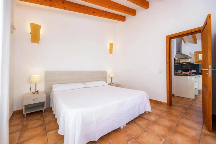 A bedroom with a neatly made bed, bedside tables, and exposed wooden ceiling beams.