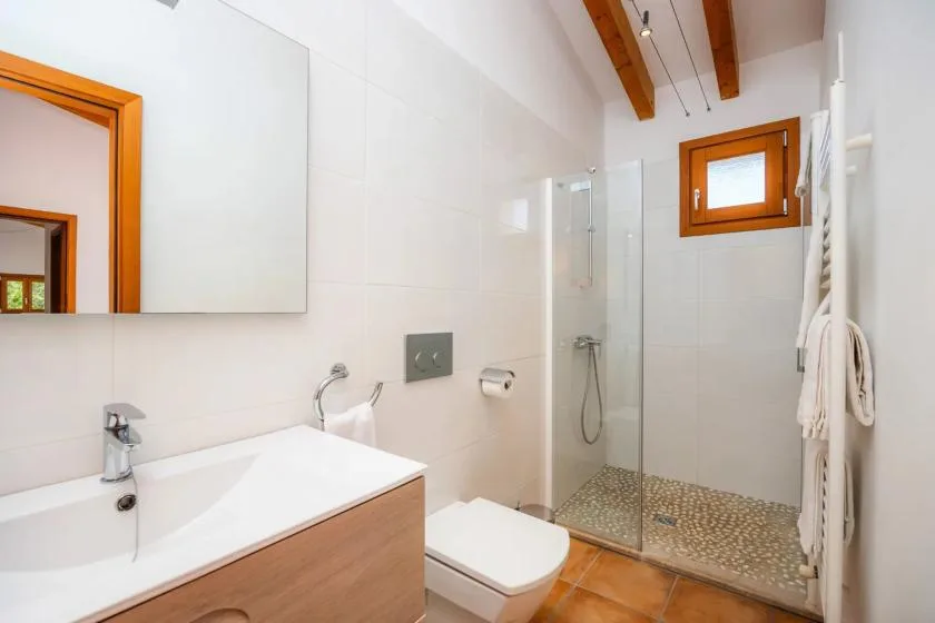 A bright bathroom with a sink, toilet, and walk-in shower.