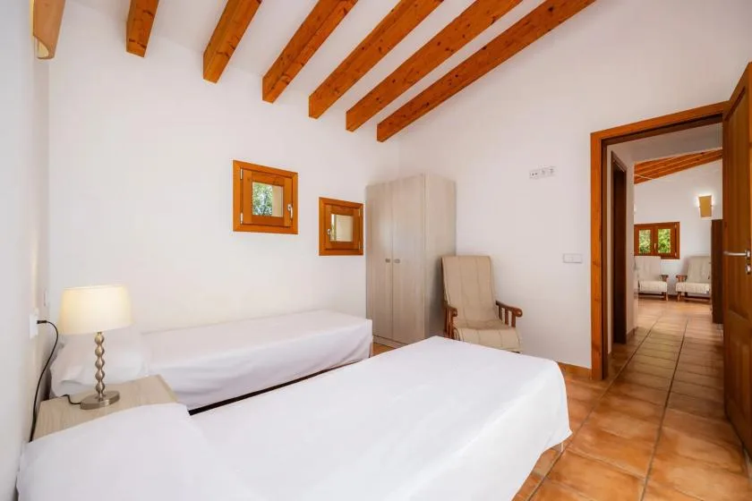 A bedroom with two beds, a wardrobe, and exposed wooden ceiling beams.