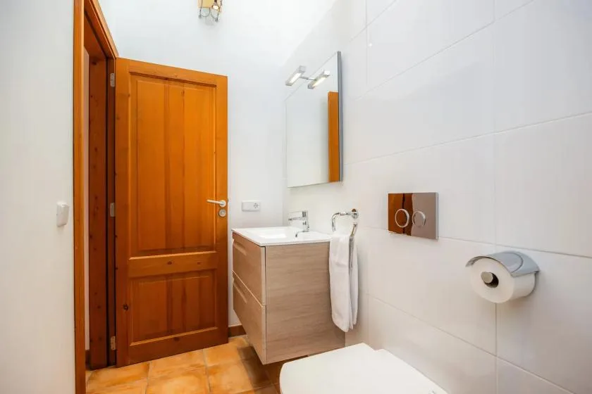 A bathroom with a vanity, mirror, and wooden door.