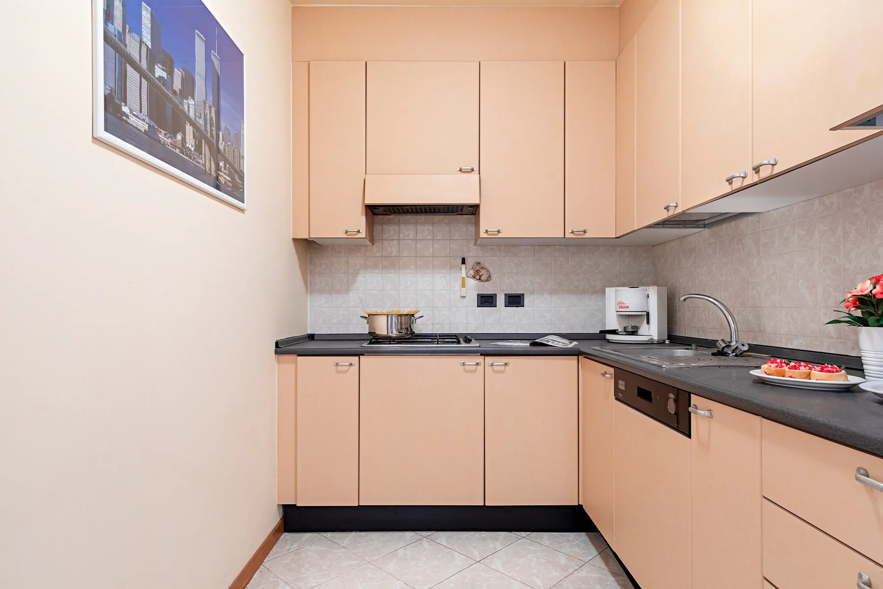 Una cocina compacta con gabinetes color durazno, encimeras oscuras y un fregadero.