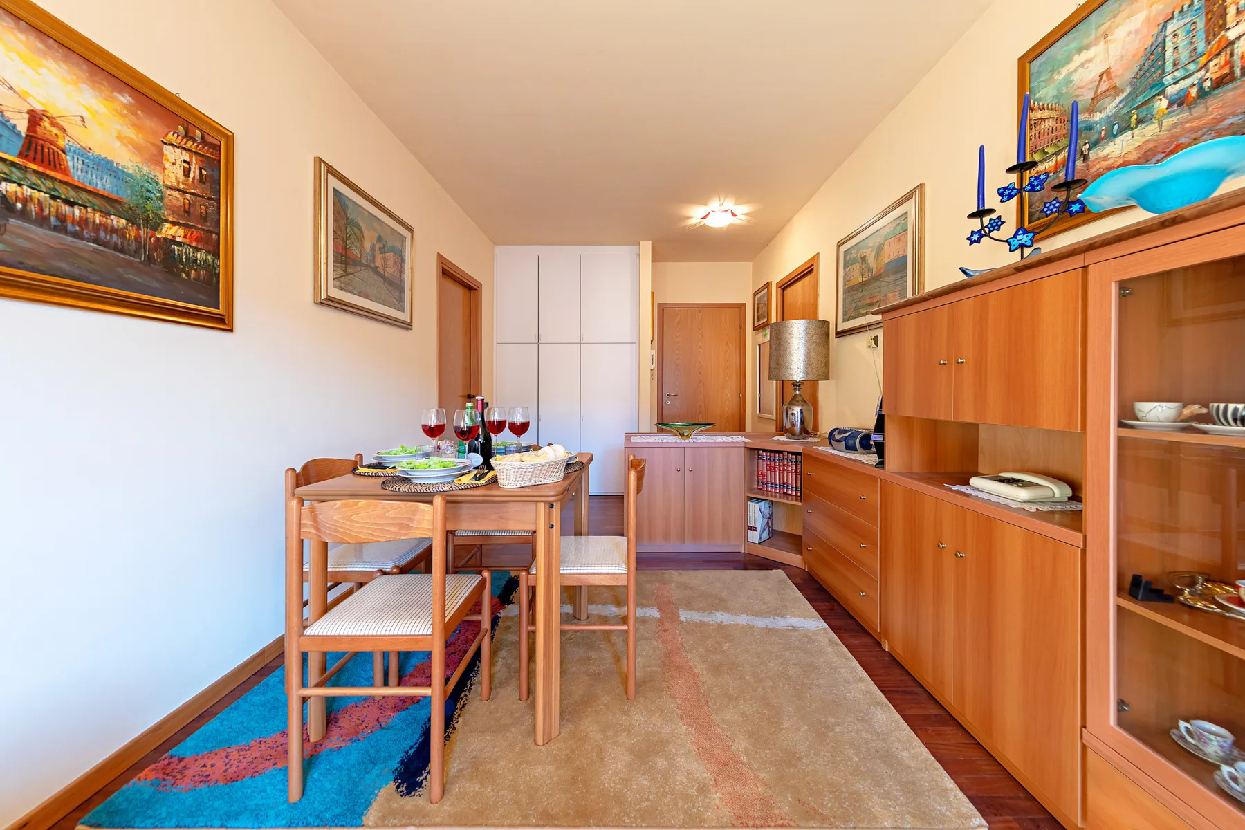 Comedor con una mesa puesta y armarios de madera.