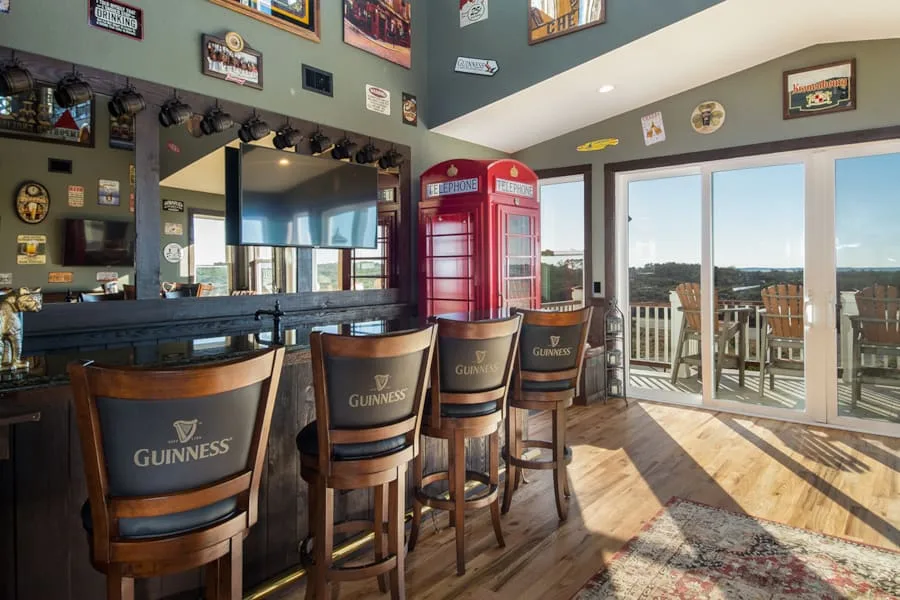 Una zona de bar con asientos, una cabina telefónica roja y grandes ventanales hacia una terraza.