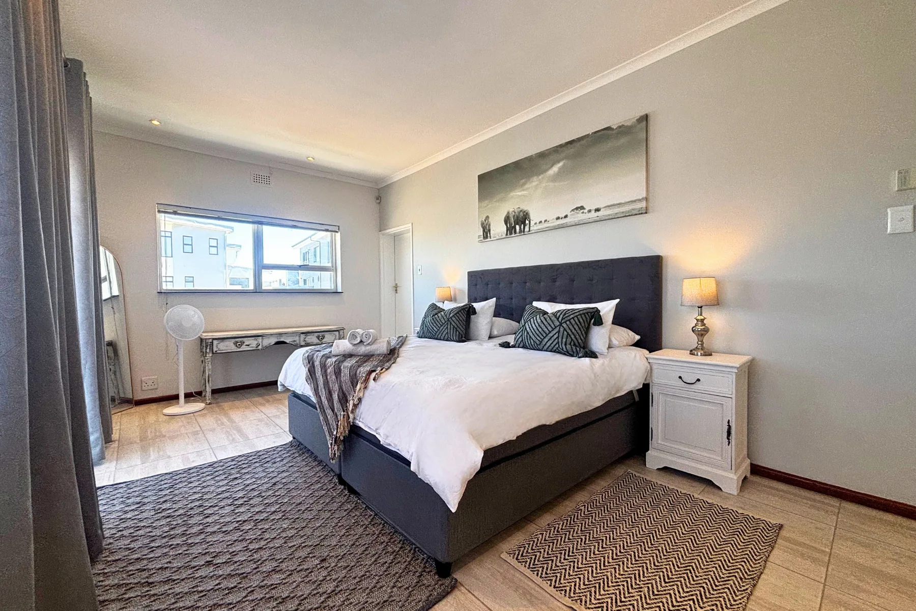A bedroom with a large bed, bedside tables, and a window.