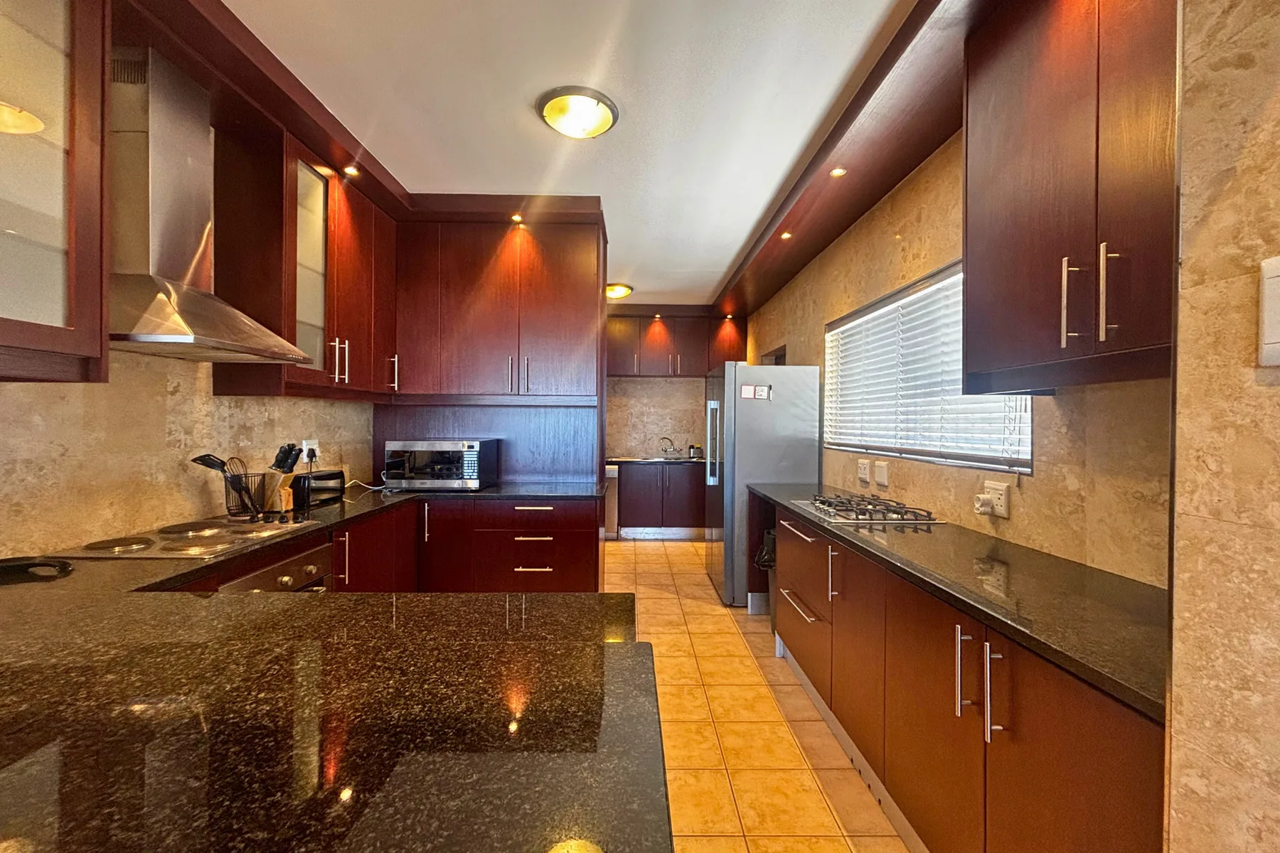 A galley kitchen with dark wood cabinets and a long countertop.