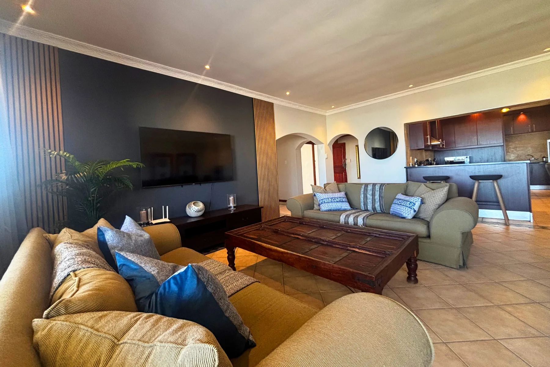 A living room with seating around a wooden coffee table and a wall-mounted television.